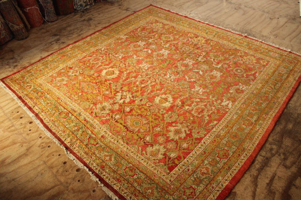 A square hand-knotted antique Ziegler wool carpet featuring a terracotta red field filled with intricate floral palmettes and framed by multi-tiered decorative borders. View VII