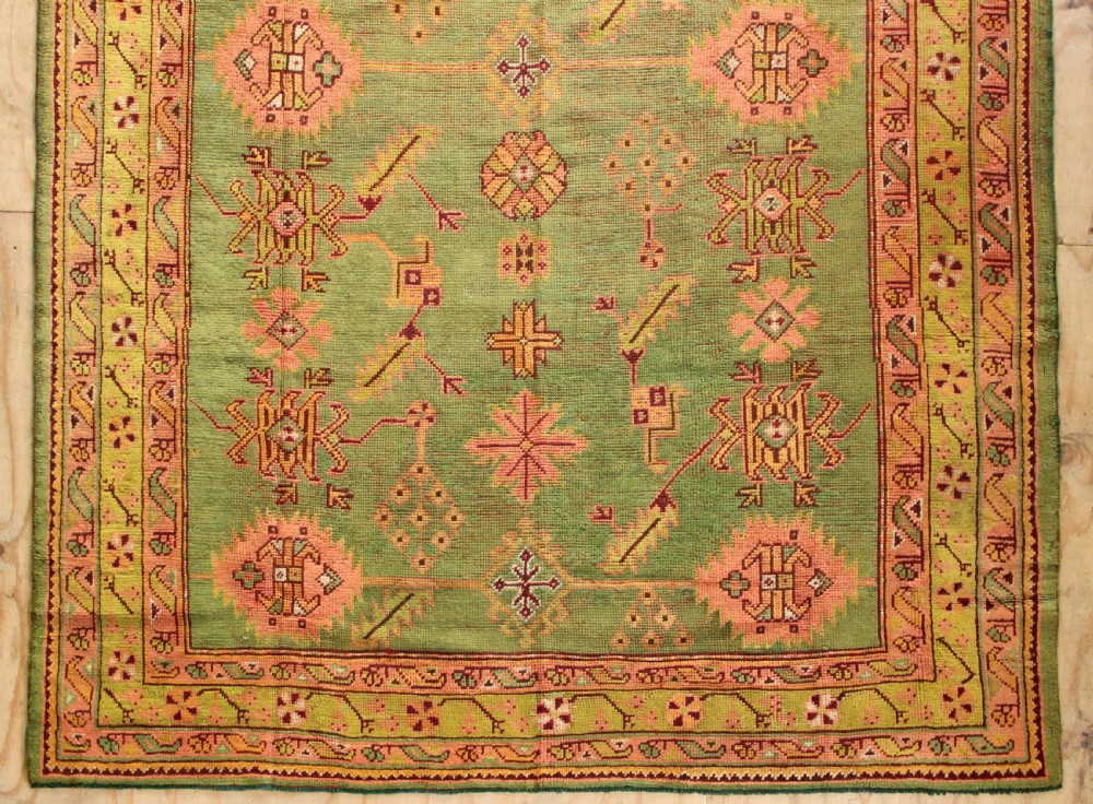 A large hand-knotted antique Oushak wool carpet featuring an olive green field with salmon pink geometric motifs and a yellow patterned border. View II