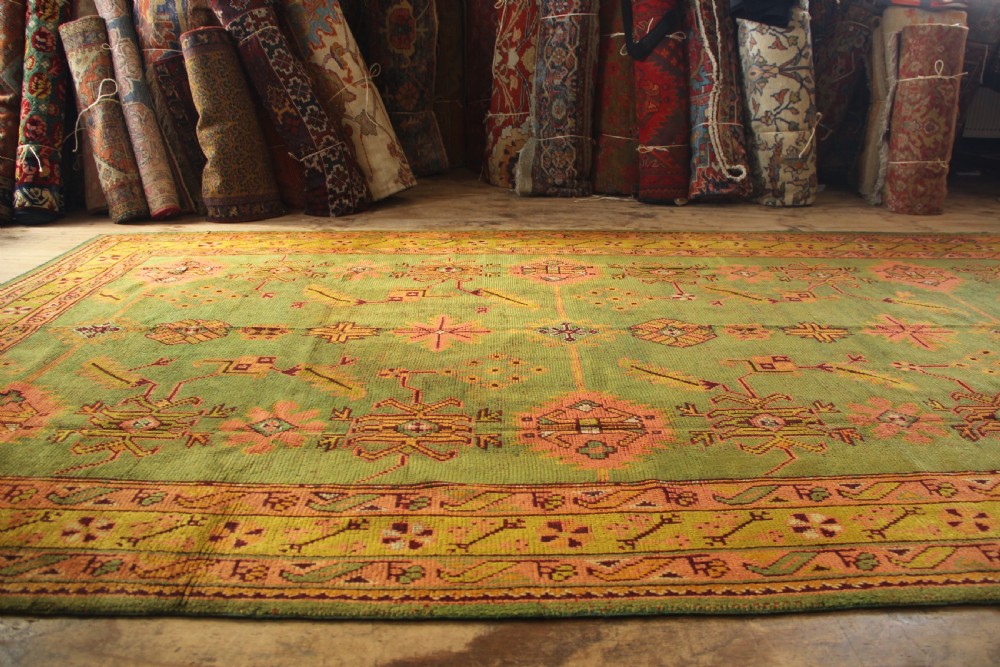 A large hand-knotted antique Oushak wool carpet featuring an olive green field with salmon pink geometric motifs and a yellow patterned border. View XI
