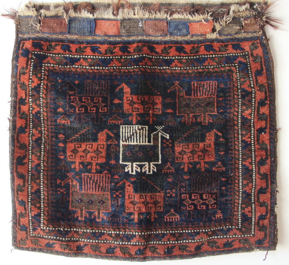 An antique square Belouch woven wool bagface decorated with stylized bird motifs in terracotta red, navy blue, and ivory accents.