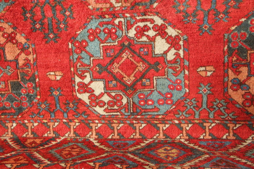A large hand-knotted wool carpet featuring repeating octagonal gul medallions and geometric borders in terracotta red, navy blue, and cream tones. View VIII