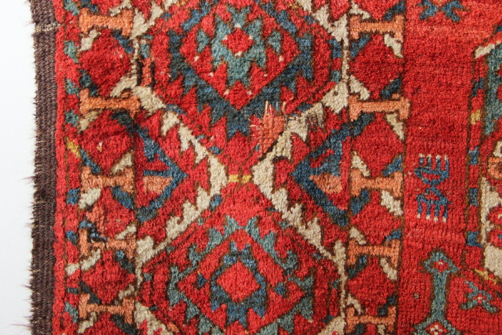 A large hand-knotted wool carpet featuring repeating octagonal gul medallions and geometric borders in terracotta red, navy blue, and cream tones. View XI