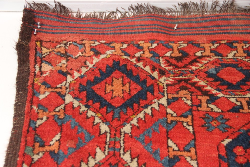 A large hand-knotted wool carpet featuring repeating octagonal gul medallions and geometric borders in terracotta red, navy blue, and cream tones. View XIII