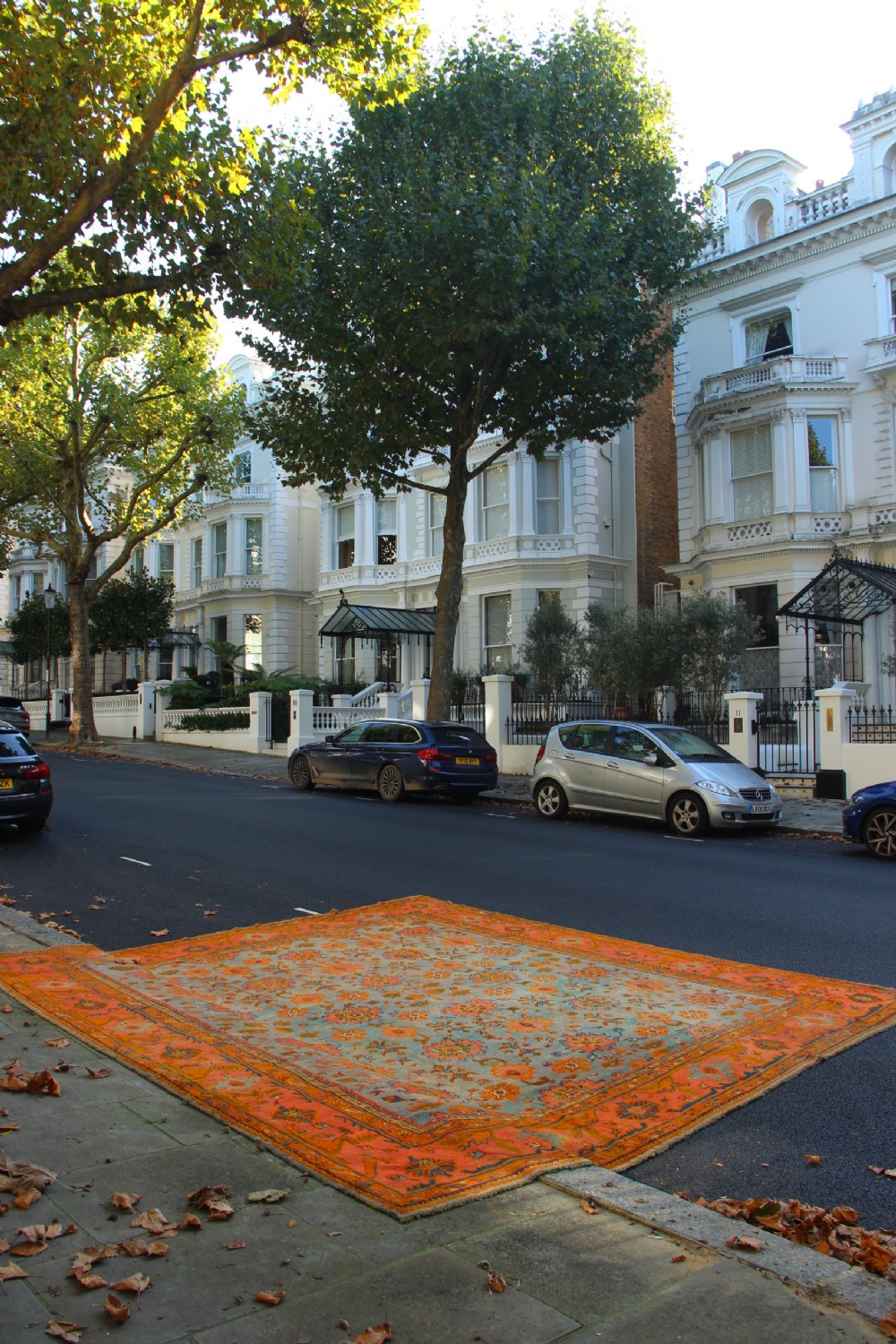 A large square antique Oushak rug with a light blue central field decorated with floral medallions and a wide terracotta and orange floral border. View VI