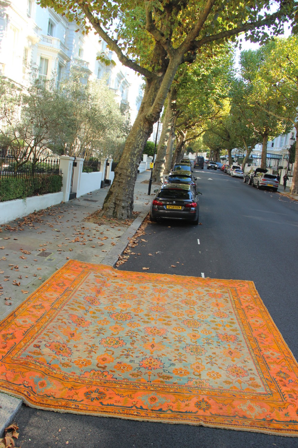 A large square antique Oushak rug with a light blue central field decorated with floral medallions and a wide terracotta and orange floral border. View VII