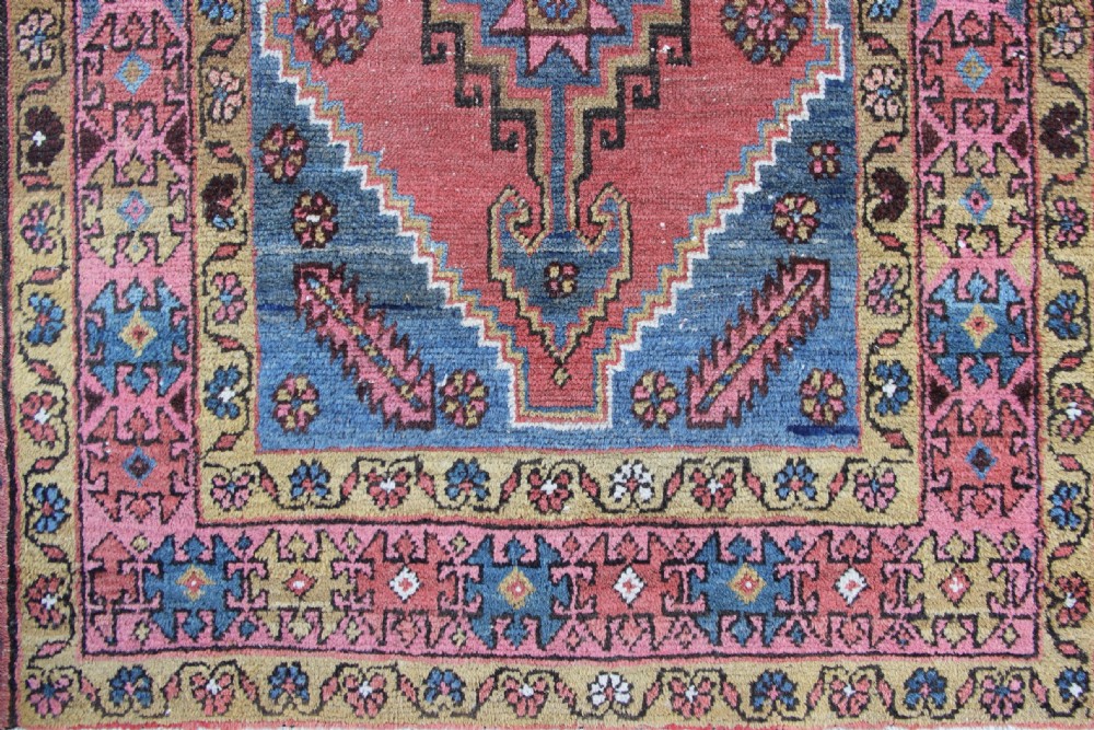 A rectangular hand-knotted antique Bakshaish Persian rug featuring a central terracotta stepped medallion field with blue spandrels and patterned floral borders. View III