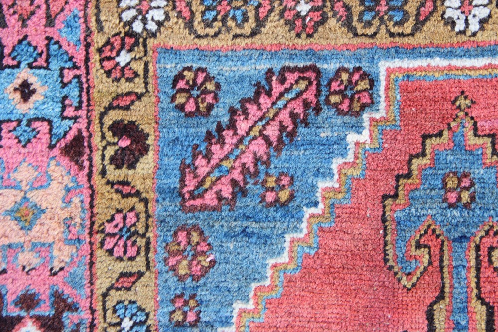 A rectangular hand-knotted antique Bakshaish Persian rug featuring a central terracotta stepped medallion field with blue spandrels and patterned floral borders. View IV
