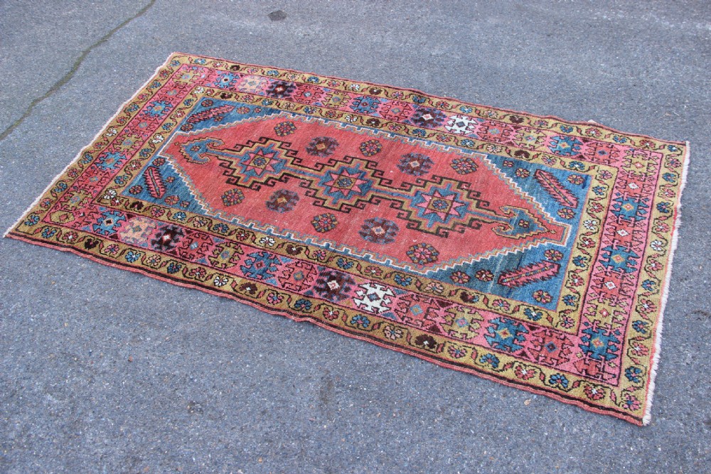 A rectangular hand-knotted antique Bakshaish Persian rug featuring a central terracotta stepped medallion field with blue spandrels and patterned floral borders. View VI