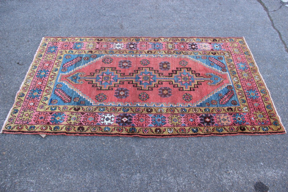 A rectangular hand-knotted antique Bakshaish Persian rug featuring a central terracotta stepped medallion field with blue spandrels and patterned floral borders. View VIII