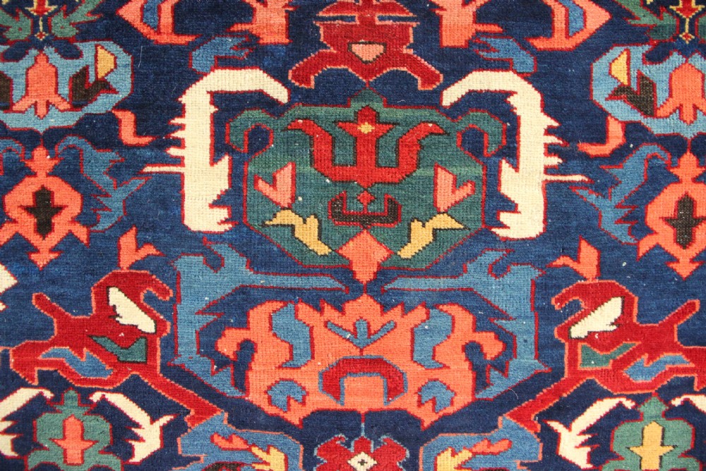 A long hand-knotted antique Caucasian Seychour rug featuring a navy blue field with red and coral geometric cross motifs and a patterned red border. View III