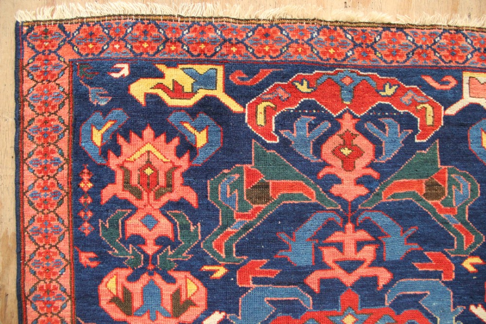 A long hand-knotted antique Caucasian Seychour rug featuring a navy blue field with red and coral geometric cross motifs and a patterned red border. View V