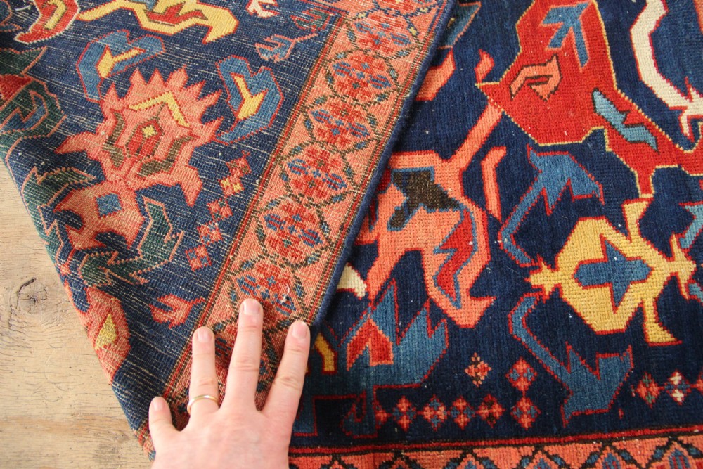 A long hand-knotted antique Caucasian Seychour rug featuring a navy blue field with red and coral geometric cross motifs and a patterned red border. View VII