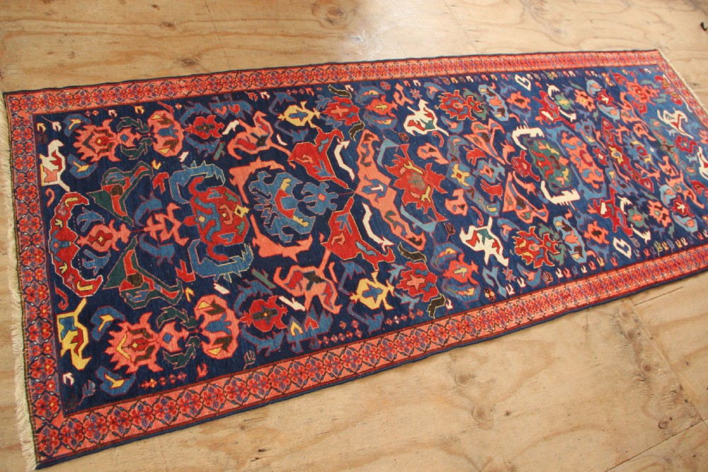 A long hand-knotted antique Caucasian Seychour rug featuring a navy blue field with red and coral geometric cross motifs and a patterned red border. View VIII