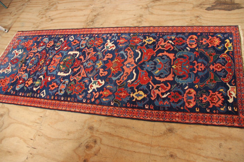 A long hand-knotted antique Caucasian Seychour rug featuring a navy blue field with red and coral geometric cross motifs and a patterned red border. View IX