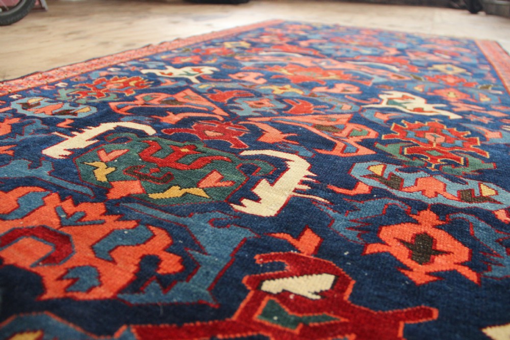 A long hand-knotted antique Caucasian Seychour rug featuring a navy blue field with red and coral geometric cross motifs and a patterned red border. View XI