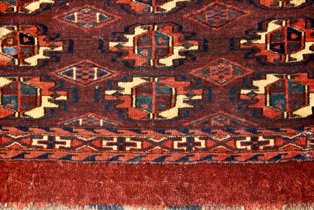 An antique hand-woven Yomud Mafrash wool textile panel featuring repeating geometric gul motifs in dark red, cream, and blue tones. View II