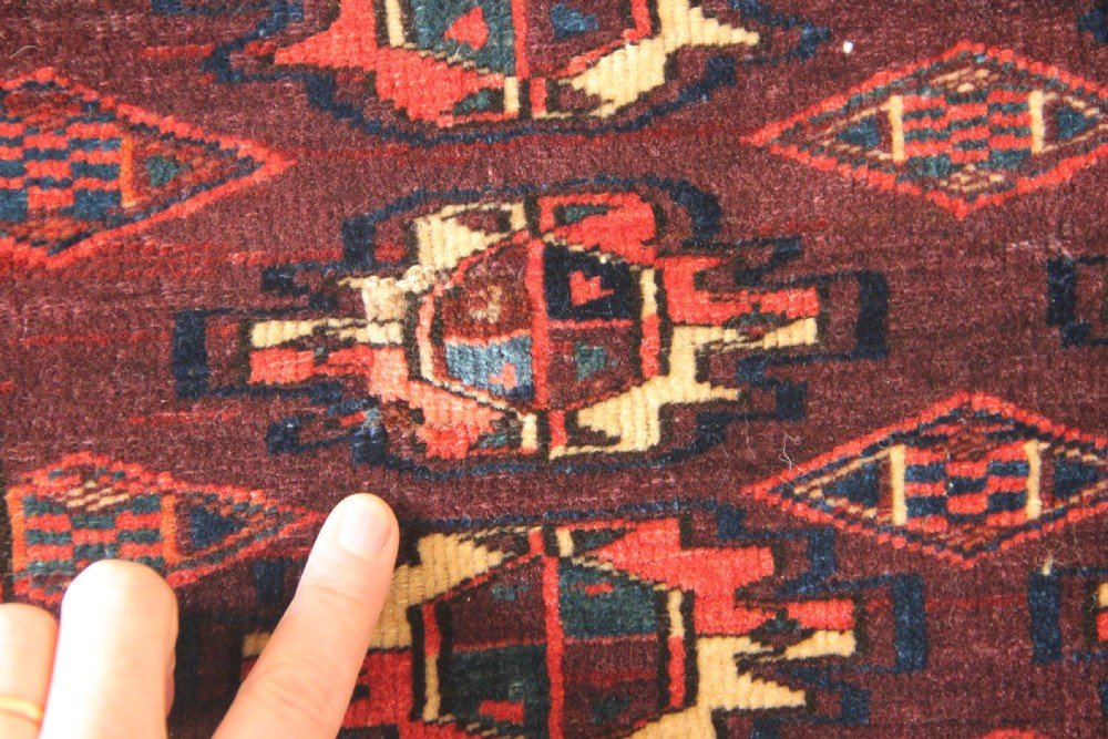 An antique hand-woven Yomud Mafrash wool textile panel featuring repeating geometric gul motifs in dark red, cream, and blue tones. View III