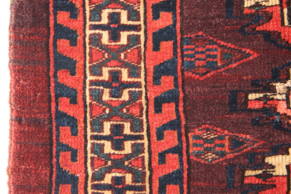 An antique hand-woven Yomud Mafrash wool textile panel featuring repeating geometric gul motifs in dark red, cream, and blue tones. View IV