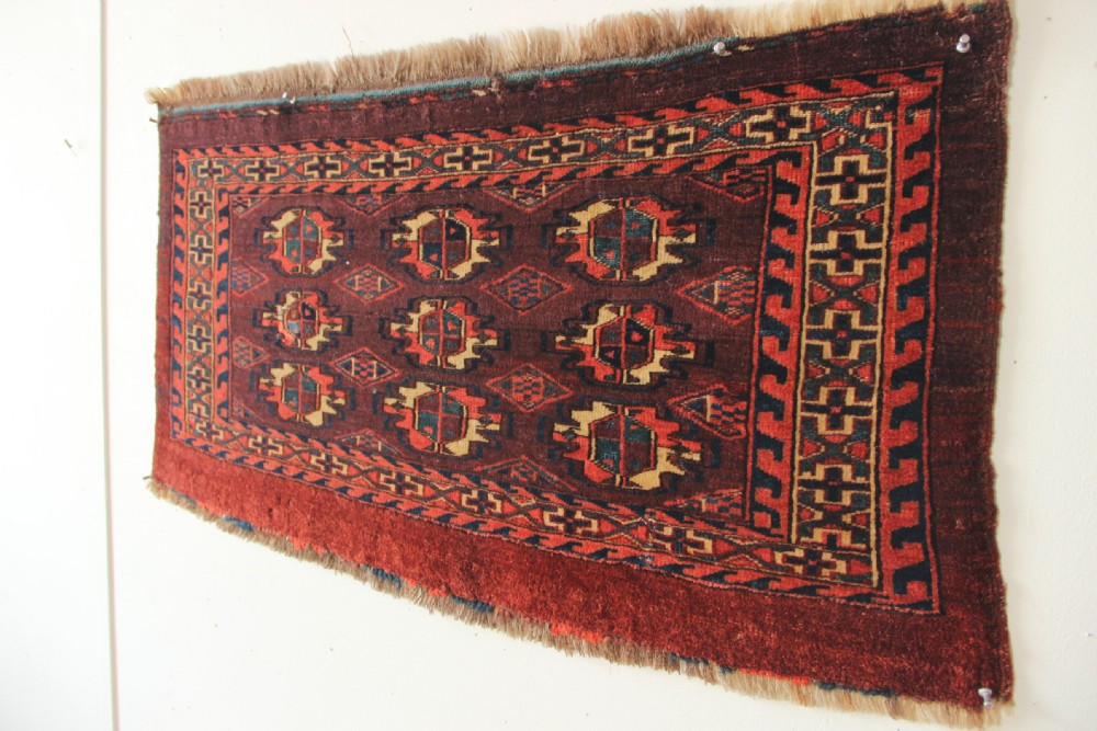 An antique hand-woven Yomud Mafrash wool textile panel featuring repeating geometric gul motifs in dark red, cream, and blue tones. View VI