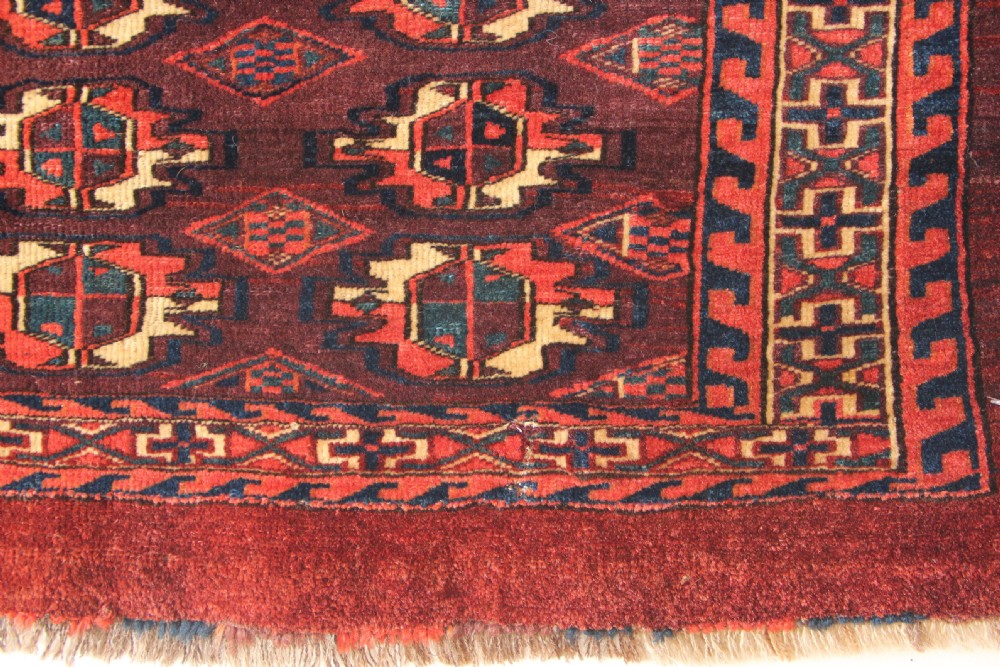 An antique hand-woven Yomud Mafrash wool textile panel featuring repeating geometric gul motifs in dark red, cream, and blue tones. View XI