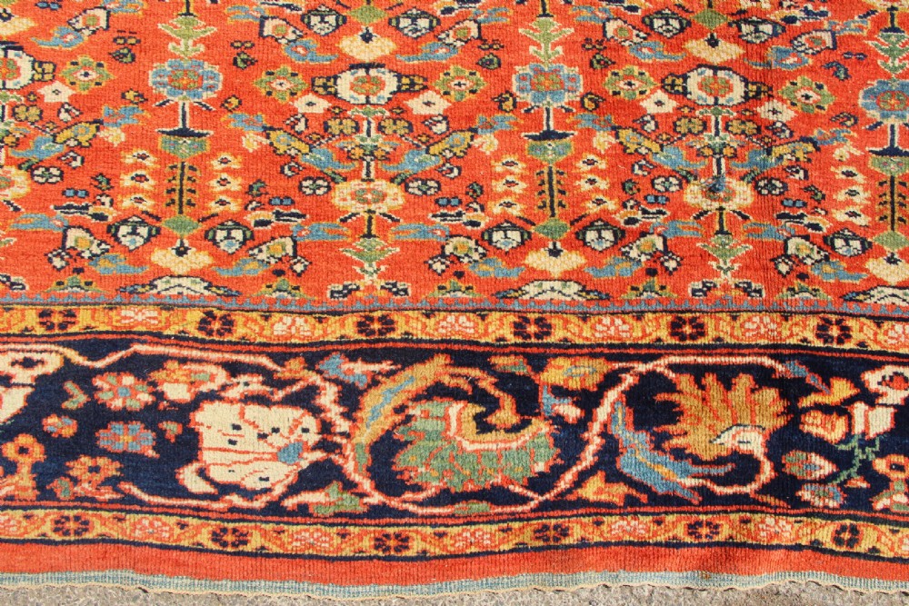 A large antique Persian Mahal carpet featuring an all-over floral lattice pattern in terracotta with a dark navy blue floral border. View V