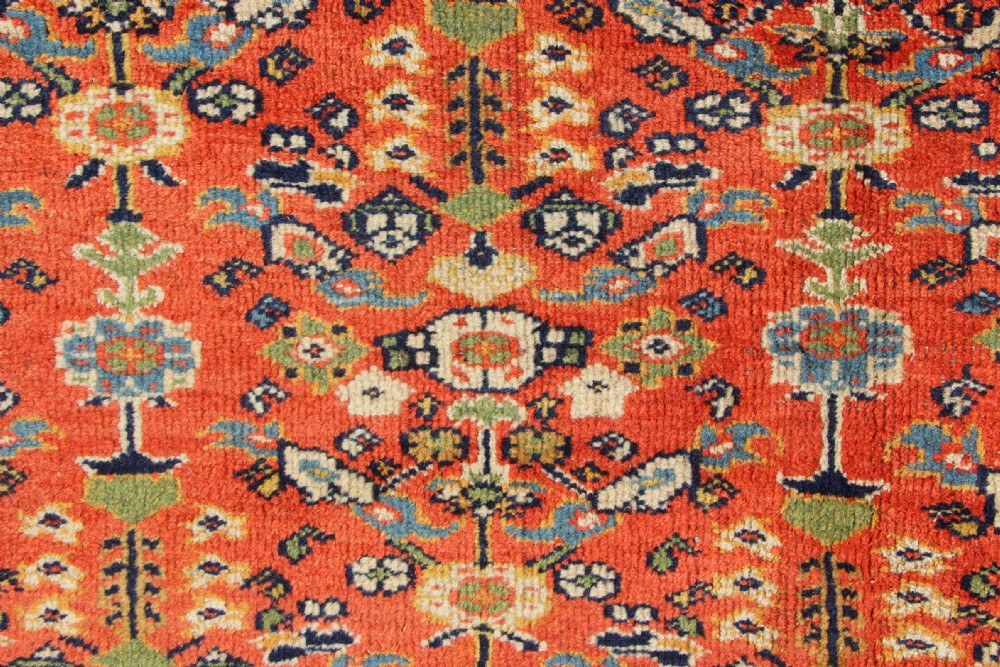 A large antique Persian Mahal carpet featuring an all-over floral lattice pattern in terracotta with a dark navy blue floral border. View VI
