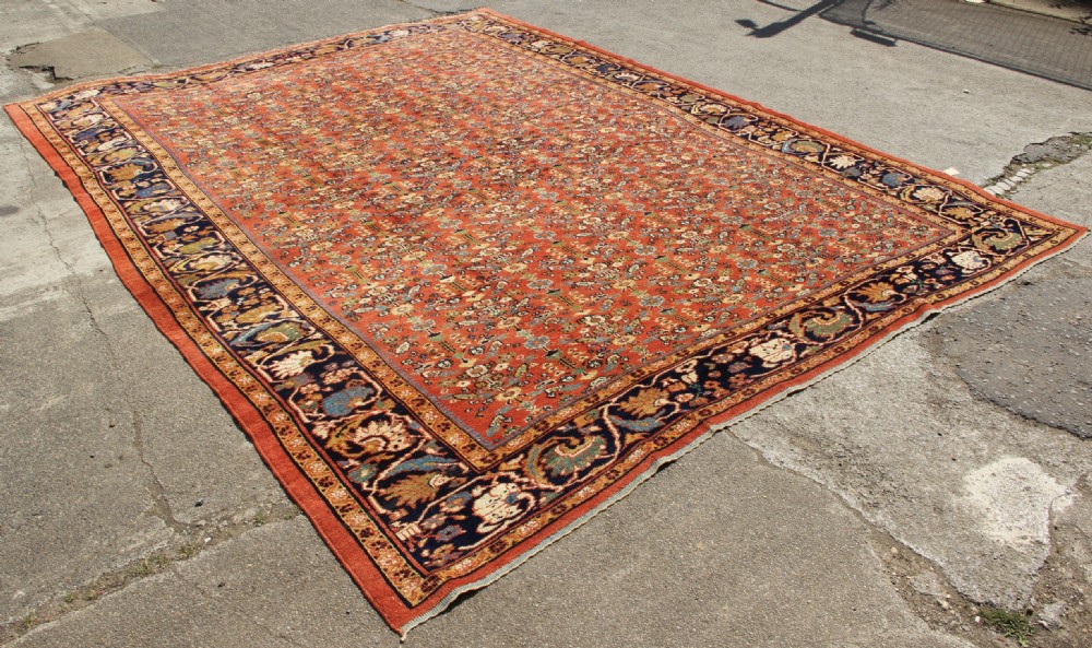 A large antique Persian Mahal carpet featuring an all-over floral lattice pattern in terracotta with a dark navy blue floral border. View IX