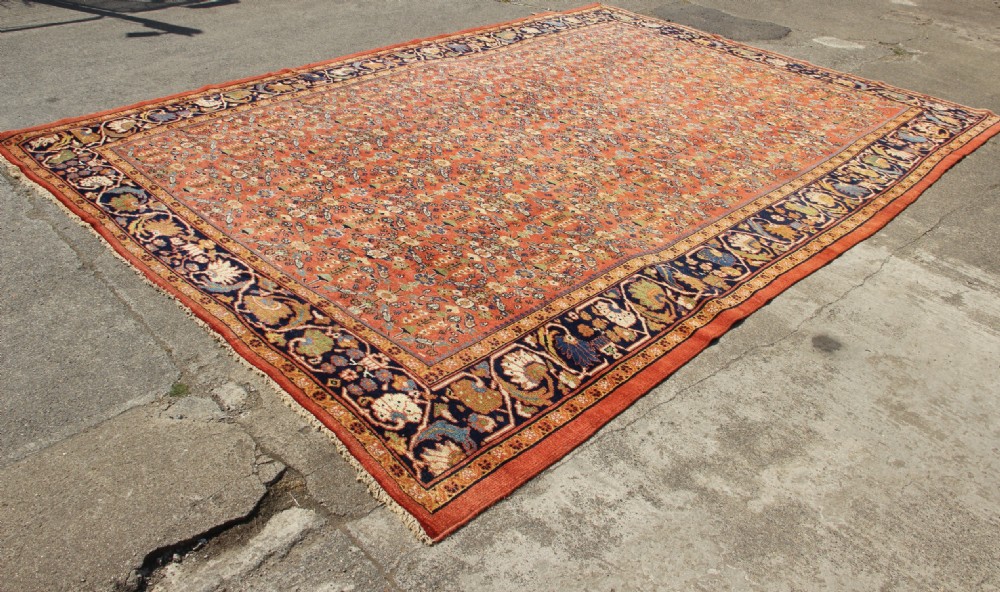 A large antique Persian Mahal carpet featuring an all-over floral lattice pattern in terracotta with a dark navy blue floral border. View X