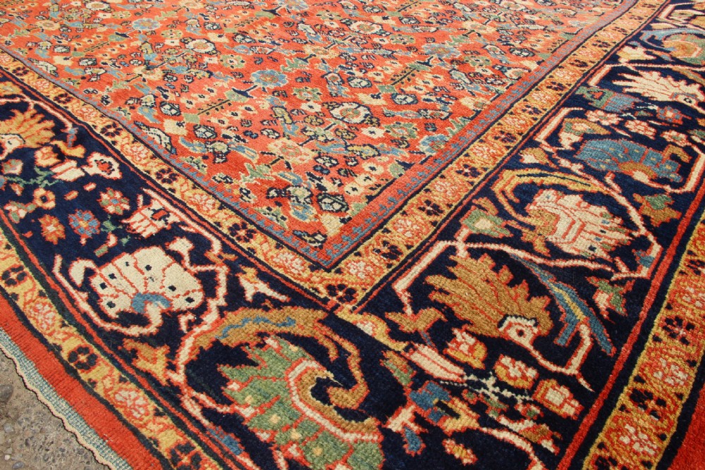 A large antique Persian Mahal carpet featuring an all-over floral lattice pattern in terracotta with a dark navy blue floral border. View XIV