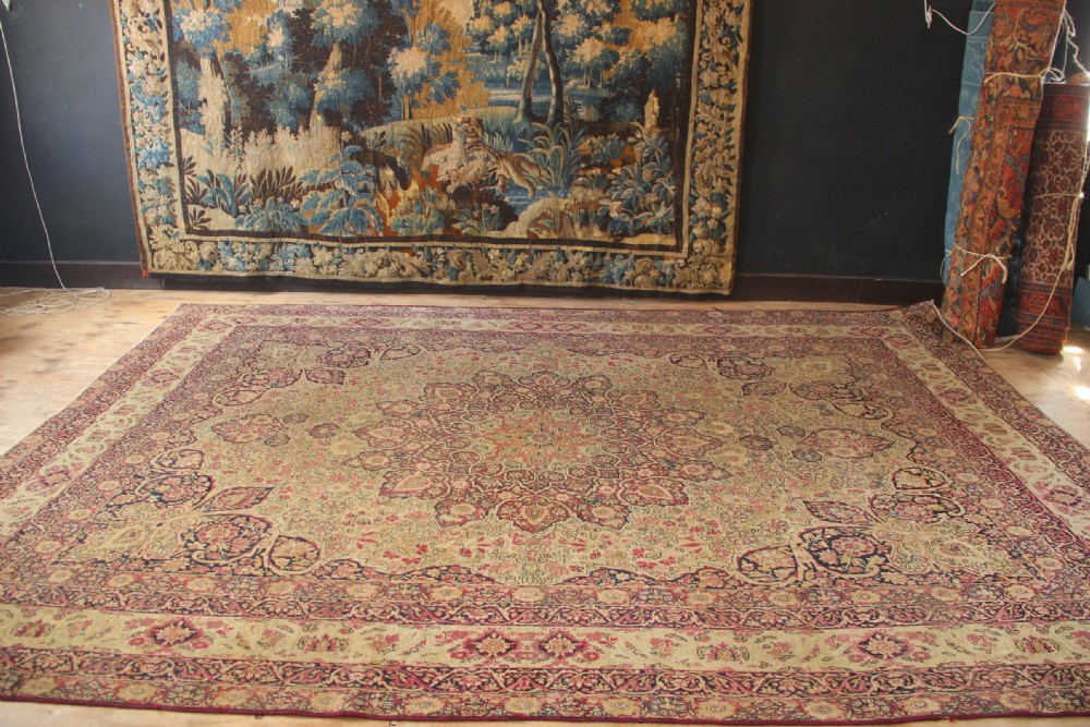 A large hand-knotted Persian Lavar Kirman carpet featuring a complex central floral medallion, intricate corner spandrels, and multi-layered decorative borders in cream, rose pink, and navy blue. View III
