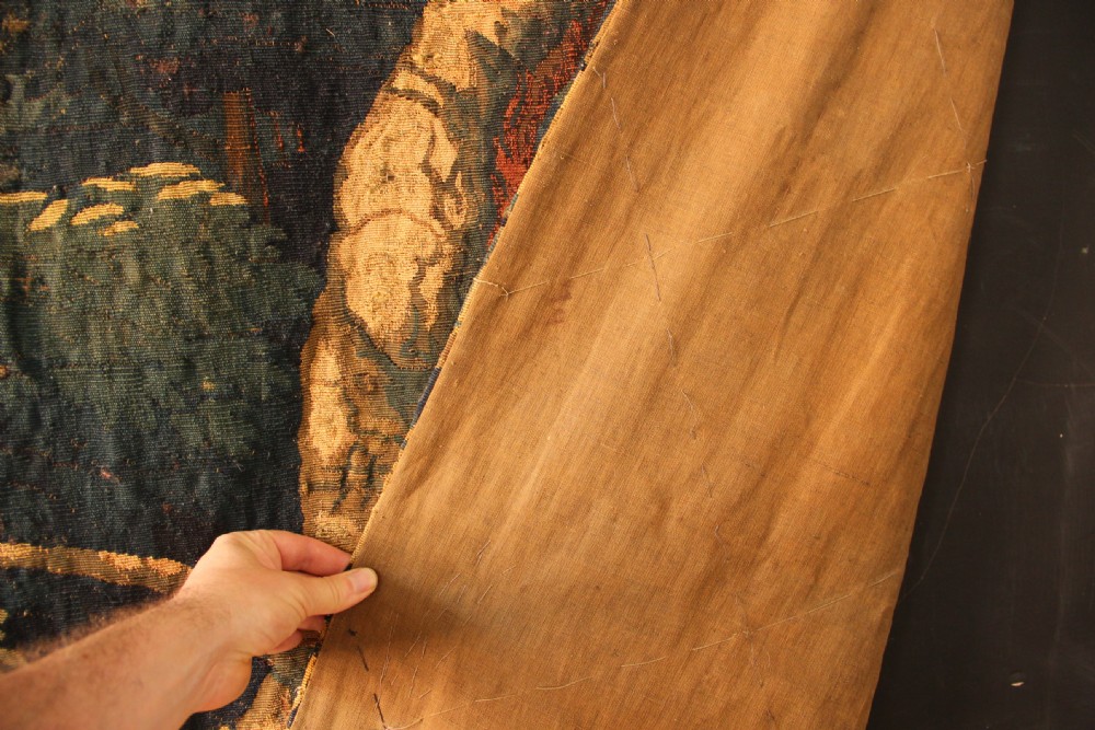 An 18th century verdure tapestry depicting a dense woodland scene with mature trees, foliage, and a distant landscape in muted greens and browns. View VIII