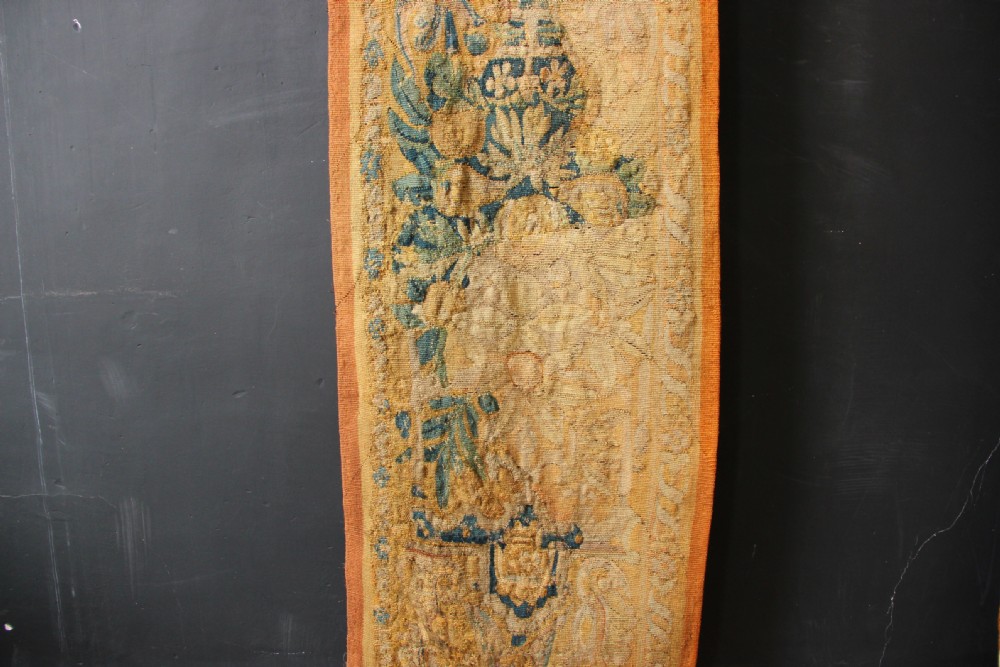A pair of long vertical 17th-century woven tapestry borders featuring botanical foliage, urns, and floral motifs in yellow, green, and blue tones. View IV