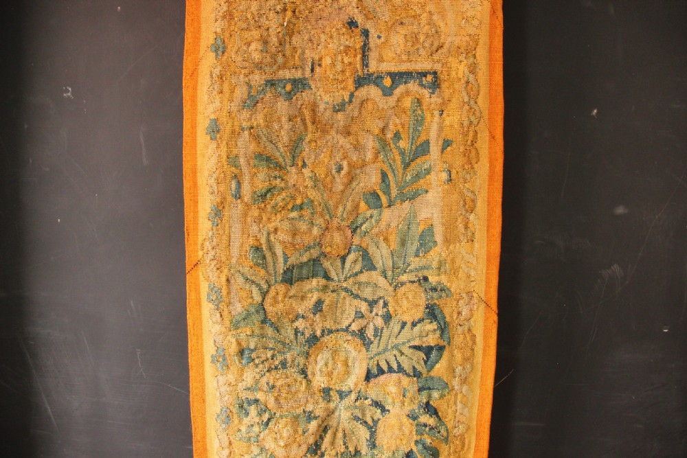 A pair of long vertical 17th-century woven tapestry borders featuring botanical foliage, urns, and floral motifs in yellow, green, and blue tones. View V