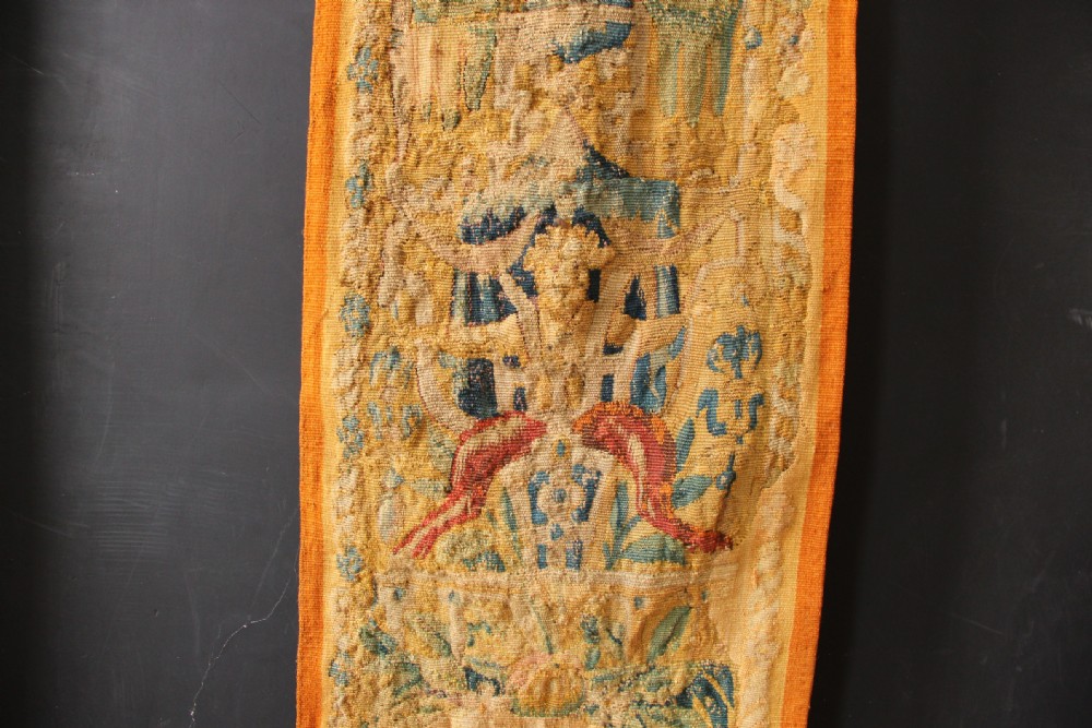 A pair of long vertical 17th-century woven tapestry borders featuring botanical foliage, urns, and floral motifs in yellow, green, and blue tones. View VI