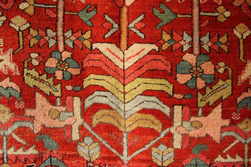 A large hand-knotted antique Heriz carpet with a rich terracotta red field, geometric floral motifs, and a navy blue central medallion. View VI