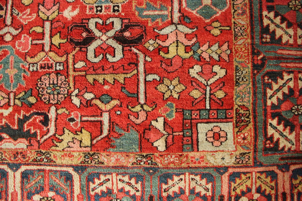 A large hand-knotted antique Heriz carpet with a rich terracotta red field, geometric floral motifs, and a navy blue central medallion. View XIII