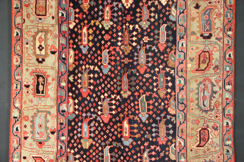 An antique Persian Serapi gallery carpet with a navy blue field featuring repeating boteh motifs framed by a wide sage green ornamental border. View II