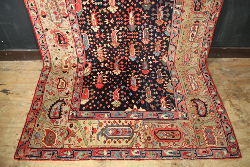 An antique Persian Serapi gallery carpet with a navy blue field featuring repeating boteh motifs framed by a wide sage green ornamental border. View III