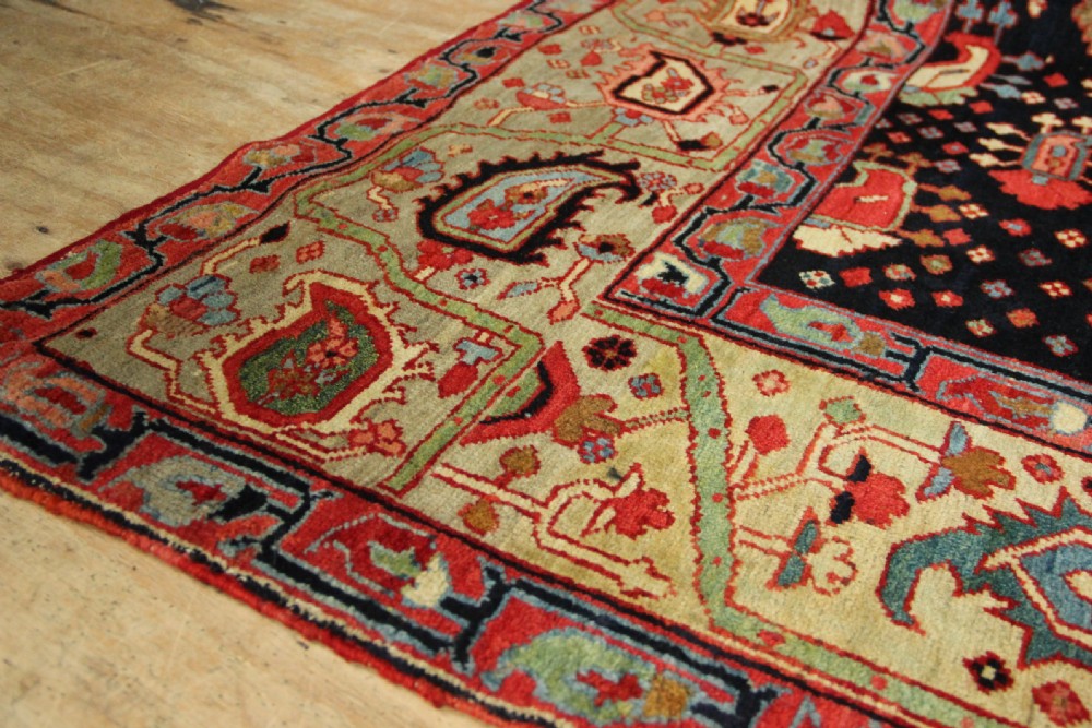 An antique Persian Serapi gallery carpet with a navy blue field featuring repeating boteh motifs framed by a wide sage green ornamental border. View IX