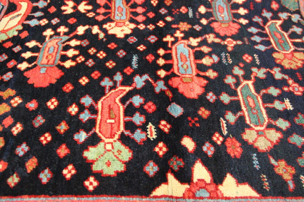 An antique Persian Serapi gallery carpet with a navy blue field featuring repeating boteh motifs framed by a wide sage green ornamental border. View XII