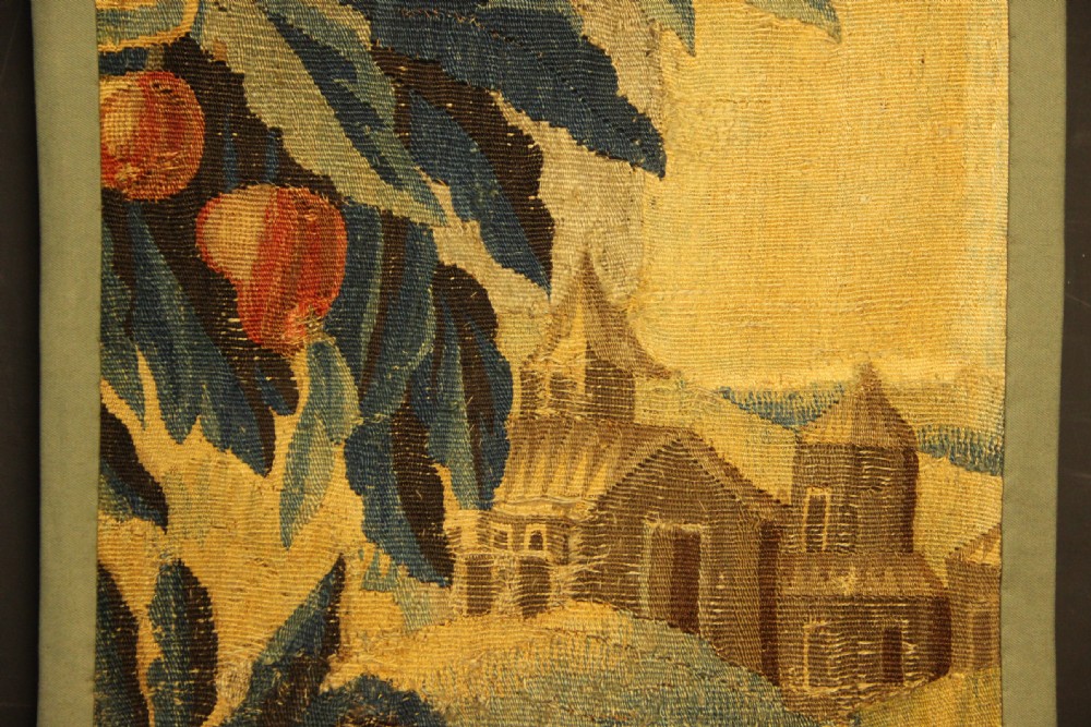 A vertical hand-woven textile panel depicting leafy foliage, fruit-bearing branches, small flowers, and a distant building in muted green, ochre, and blue tones. View II
