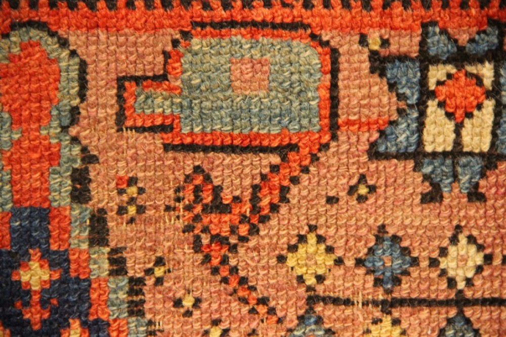 An early nineteenth-century Anatolian Konya yastik rug featuring a central navy blue diamond medallion set against a terracotta woven background with geometric borders. View IV