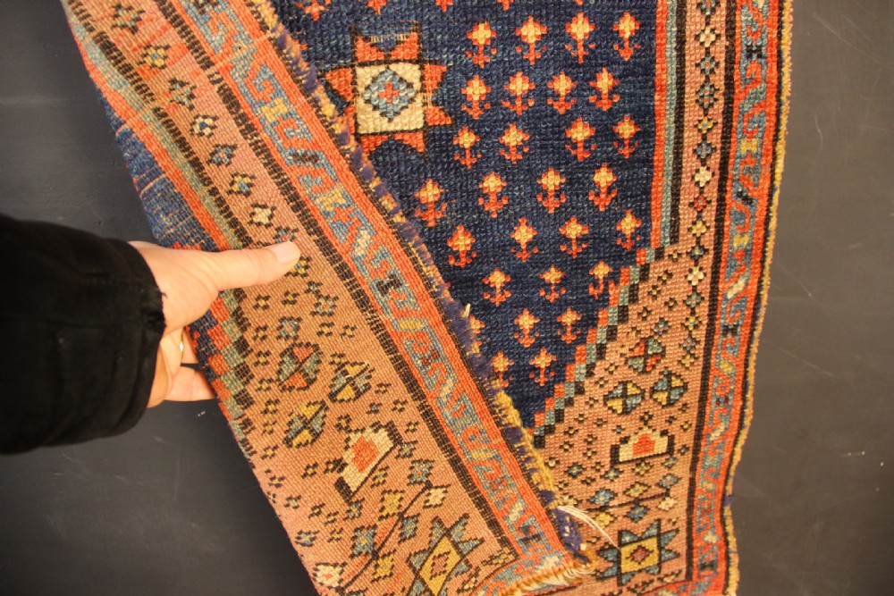 An early nineteenth-century Anatolian Konya yastik rug featuring a central navy blue diamond medallion set against a terracotta woven background with geometric borders. View VI