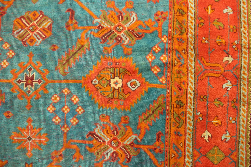 An antique Oushak wool rug displaying a teal field with geometric orange motifs and multi-layered terracotta borders. View XI