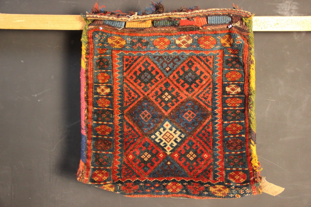 An antique handwoven Jaf Kurd wool saddlebag face featuring diamond latch-hook medallions in red, blue, and yellow.