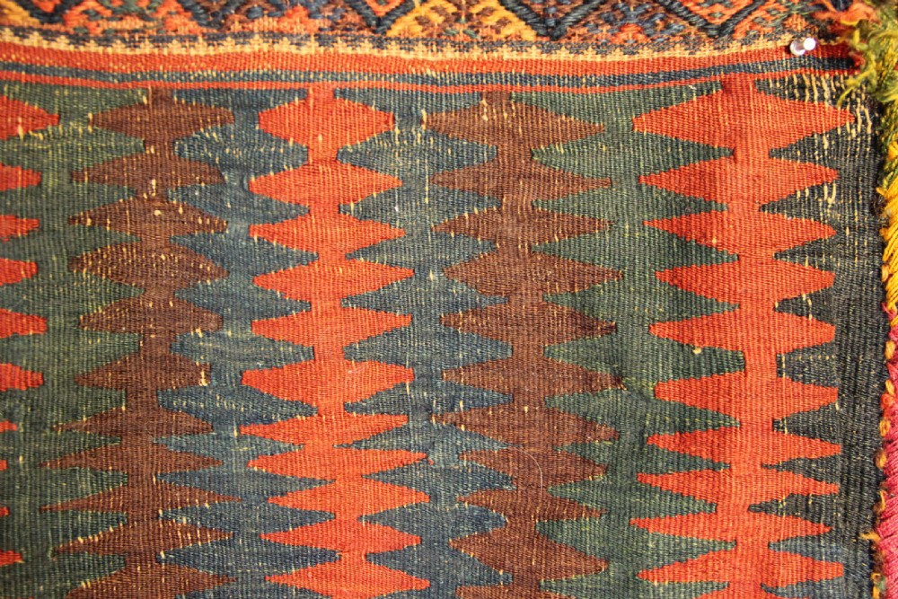 An antique handwoven Jaf Kurd wool saddlebag face featuring diamond latch-hook medallions in red, blue, and yellow. View III