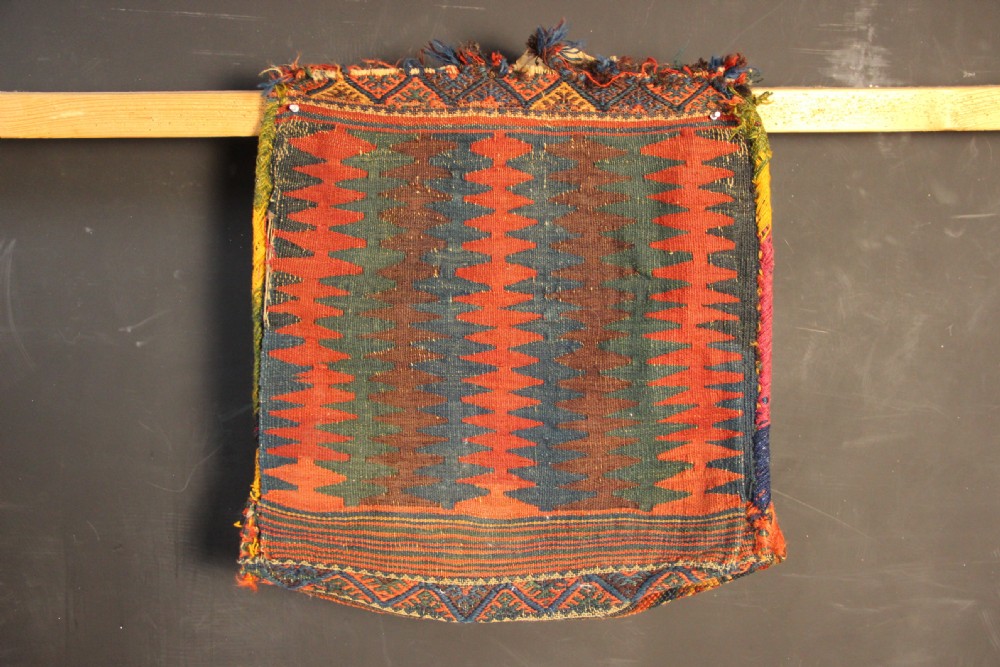 An antique handwoven Jaf Kurd wool saddlebag face featuring diamond latch-hook medallions in red, blue, and yellow. View IV