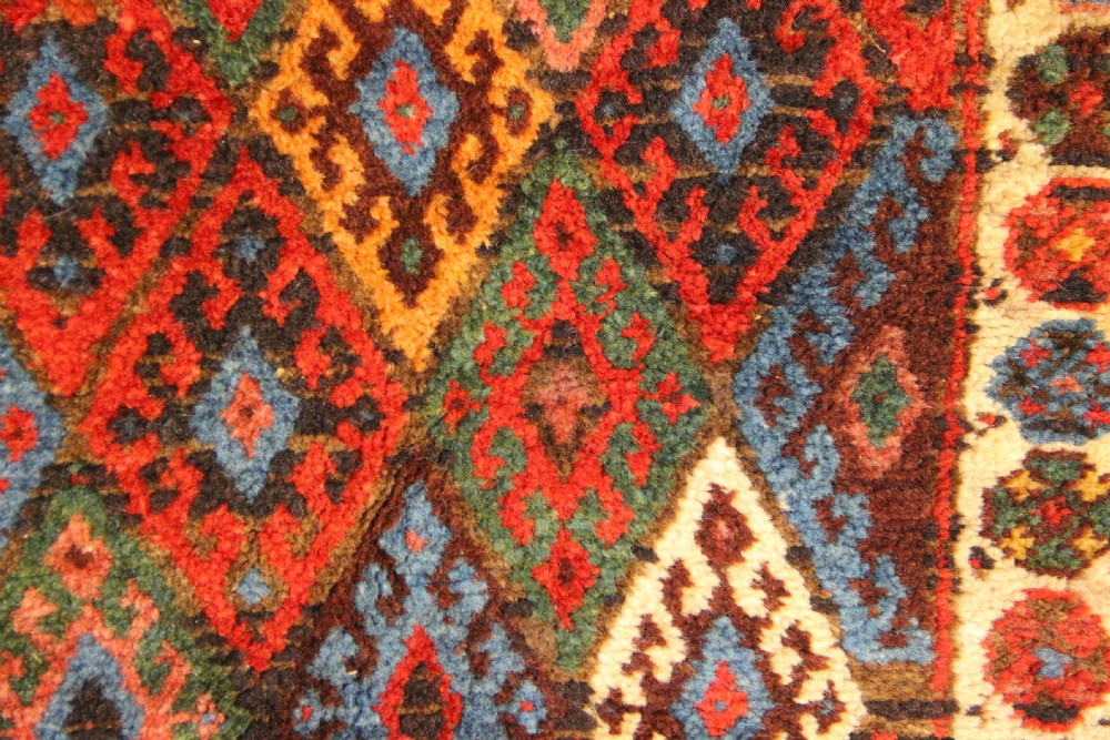 A square antique hand-knotted Jaf Kurd wool saddlebag face with geometric diamond lattice patterns in red, blue, green, and cream tones. View II