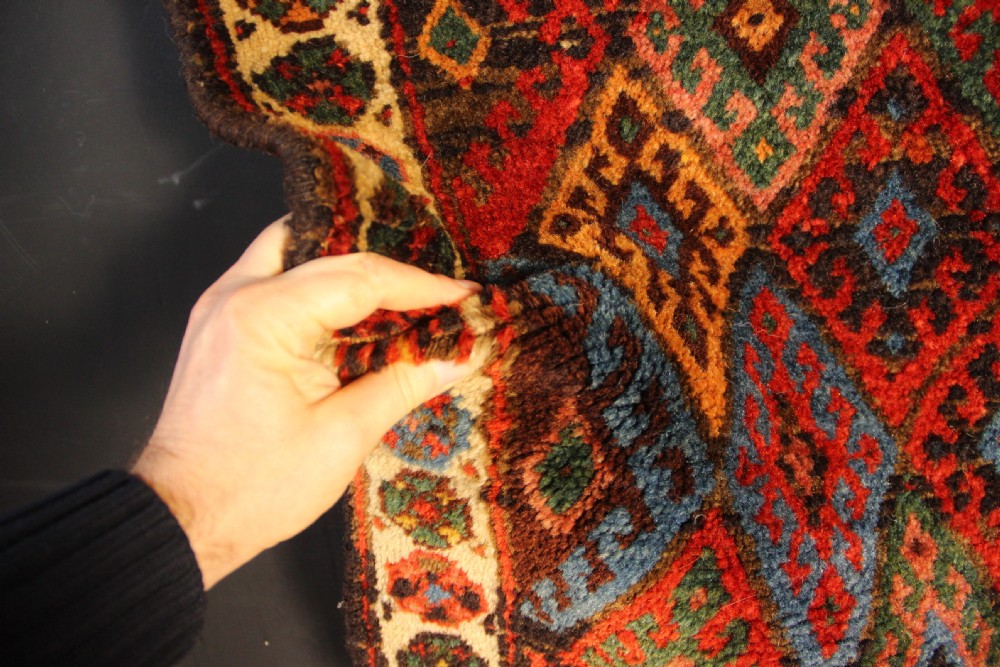 A square antique hand-knotted Jaf Kurd wool saddlebag face with geometric diamond lattice patterns in red, blue, green, and cream tones. View III