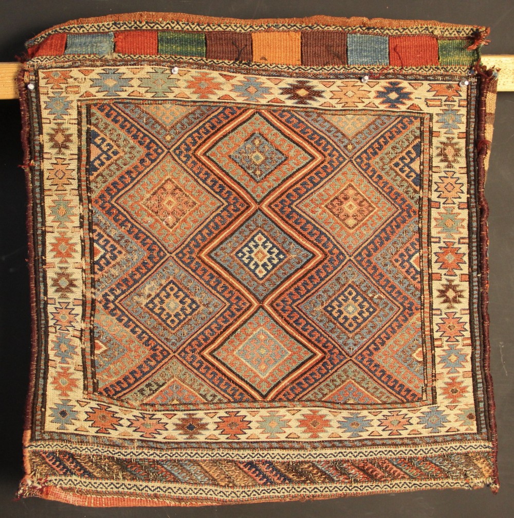 An antique square Shahsavan Soumac woven saddlebag face featuring geometric diamond medallions in terracotta red, navy, and soft blue wool.